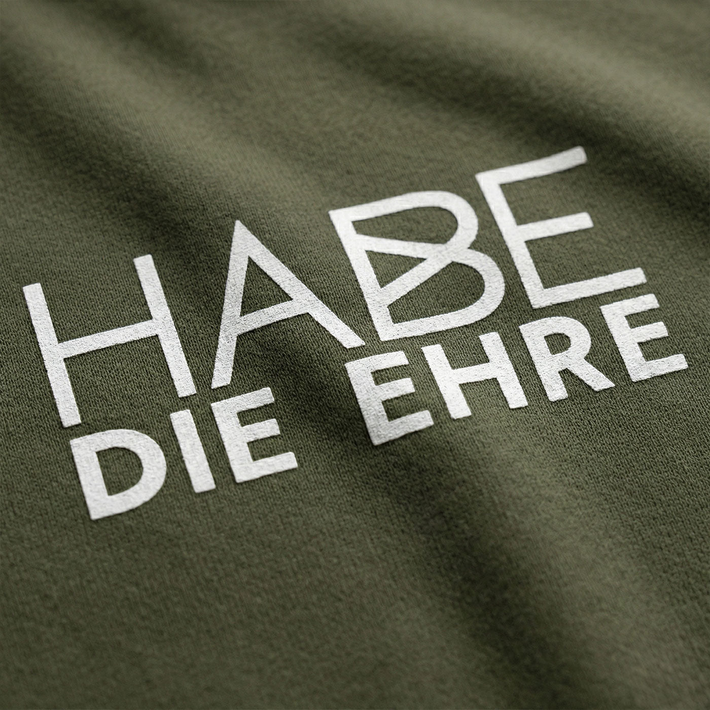 Grüner Hoodie mit weißem Aufdruck "HABE DIE EHRE" und feiner Stoffstruktur, sichtbare Falten des Stoffes