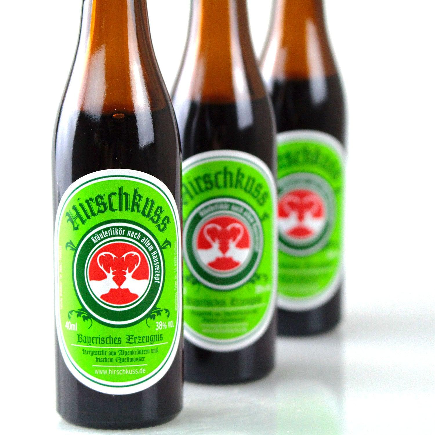 Dunkelbrauner Kräuterlikör in klarer Glasflasche mit rotem Schraubverschluss und Hirsch-Motiv, 38 % vol., 0,04 l