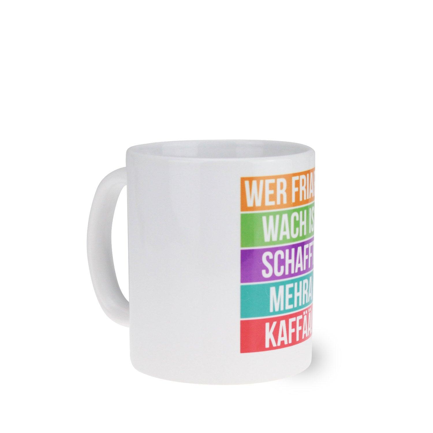 Weiße Keramiktasse mit schwarzem Henkel und Schriftzug „Wer friara wach is, schafft mehra Kaffää“ gegenüber dem Henkel.