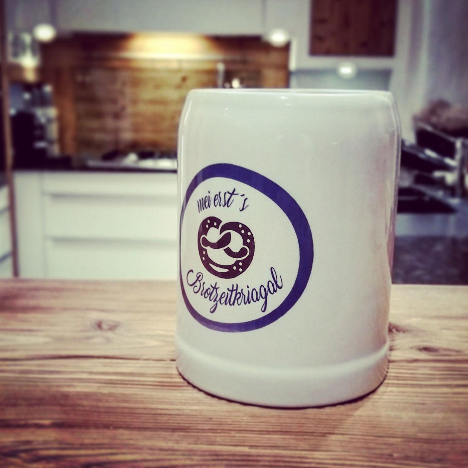 Kleiner Steinkrug für Kinder mit bauchiger Form, grauer Oberfläche und blauem Schriftzug „Mei erst’s Brotzeitkriagal“, 0,25 l.
