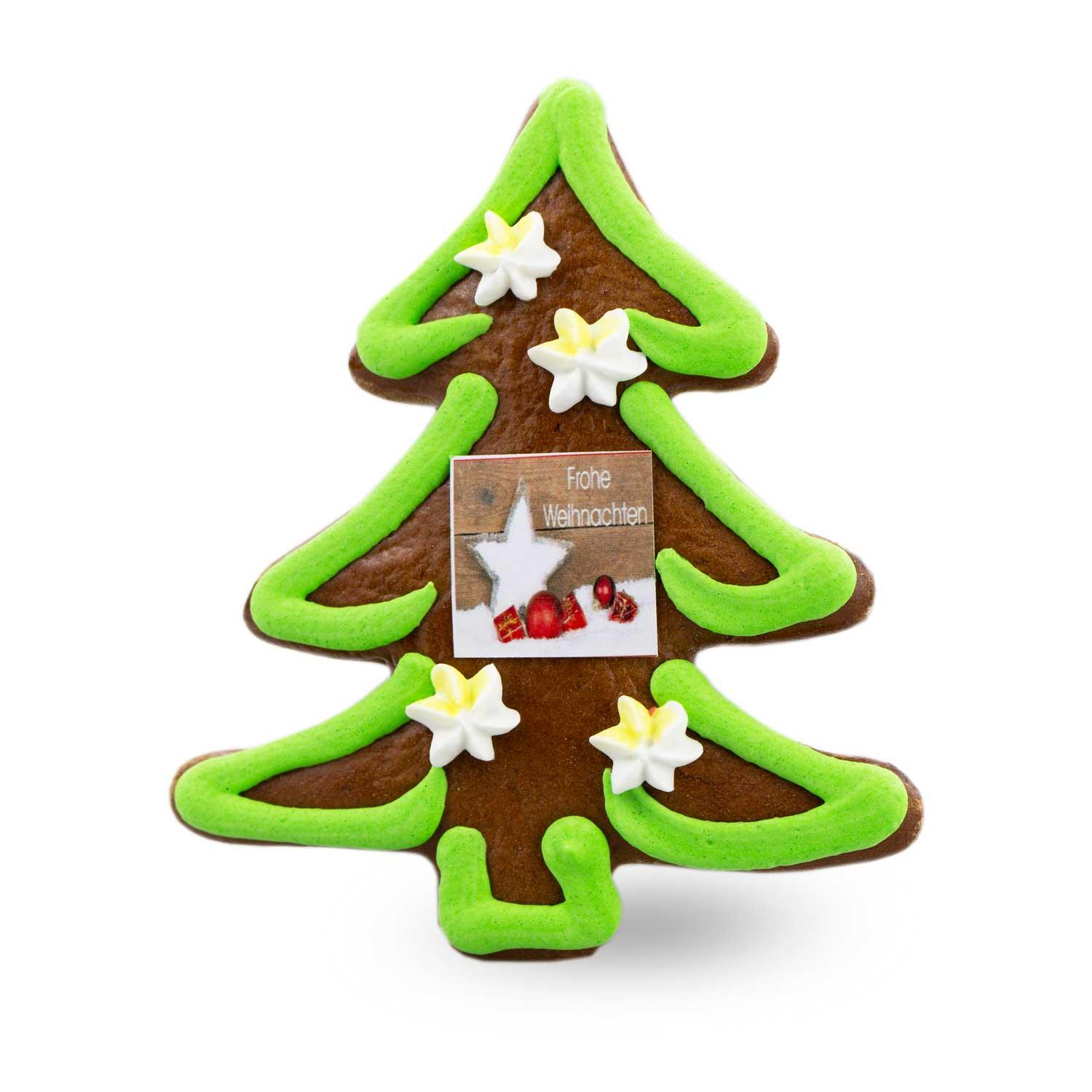 Lebkuchen in Tannenbaumform mit weißer Zuckerschrift „Frohes Fest“, verziert mit grünem Zuckerguss und bunten Streuseln.