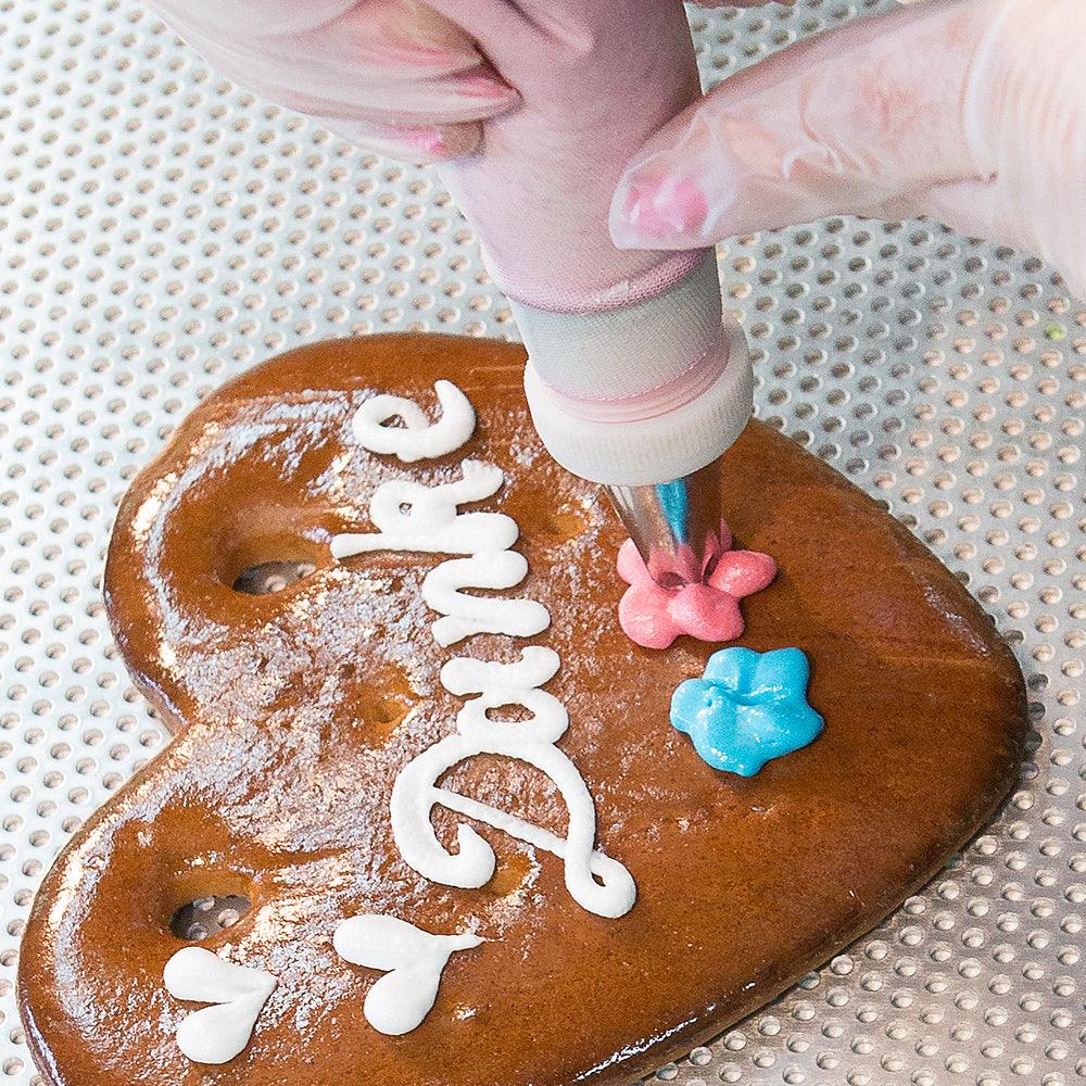 Herzförmiges Lebkuchenherz mit weißer Umrandung, rosablauer Dekor und Schriftzug „Gratulation Bua“, 14 × 17 cm, 100 g.