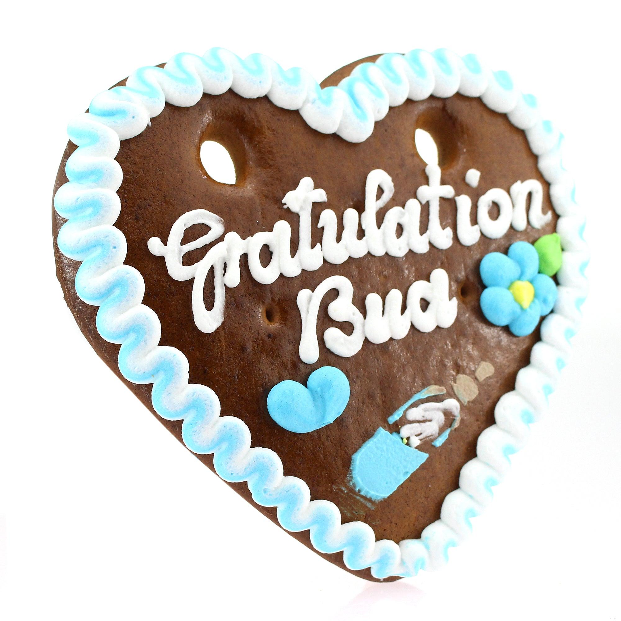 Herzförmiger Lebkuchen mit weißer Zuckerschrift „Gratulation Bua“ und rot-weißem Rand aus Zuckerguss.