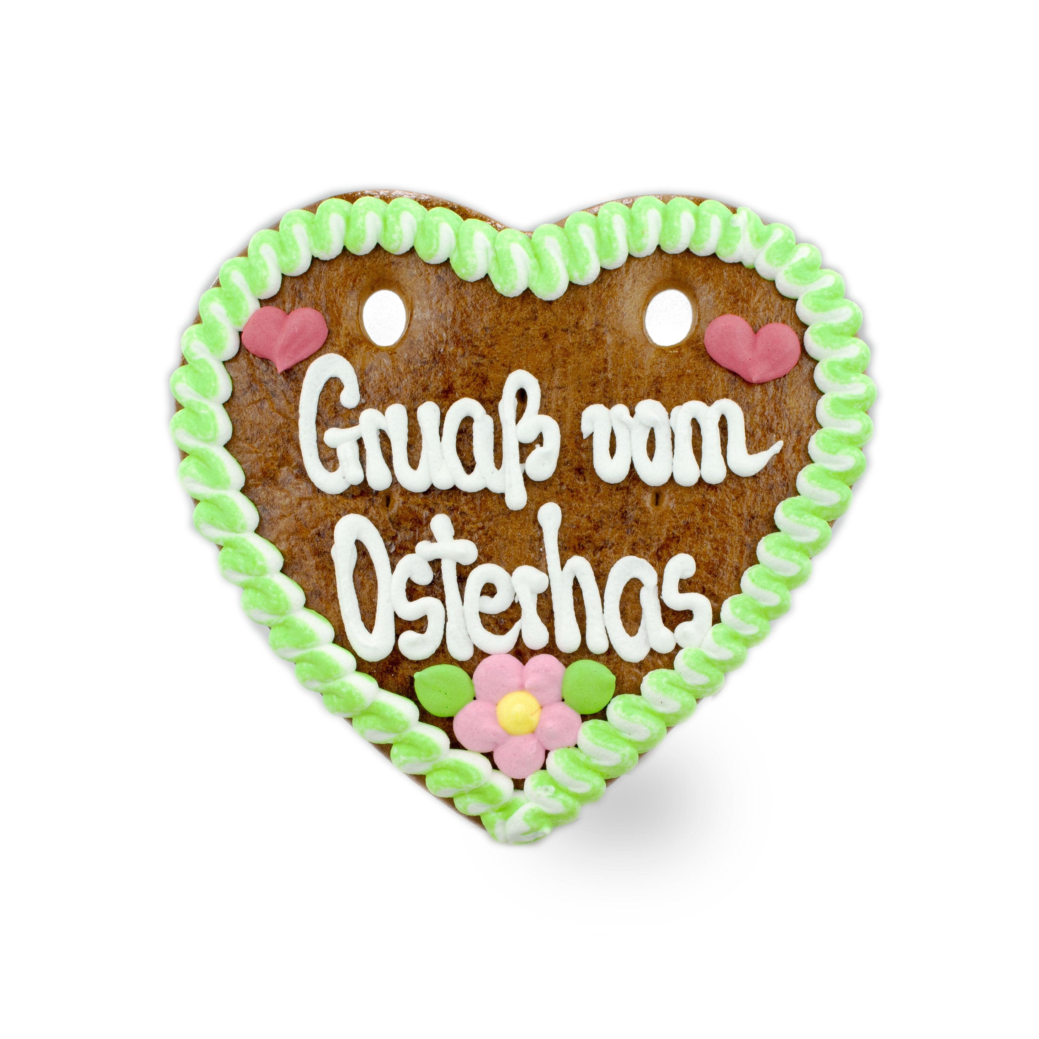 Herzförmiger Lebkuchen mit weißer Zuckerschrift „Gruaß vom Osterhas“ und bunter Zuckerdekoration.