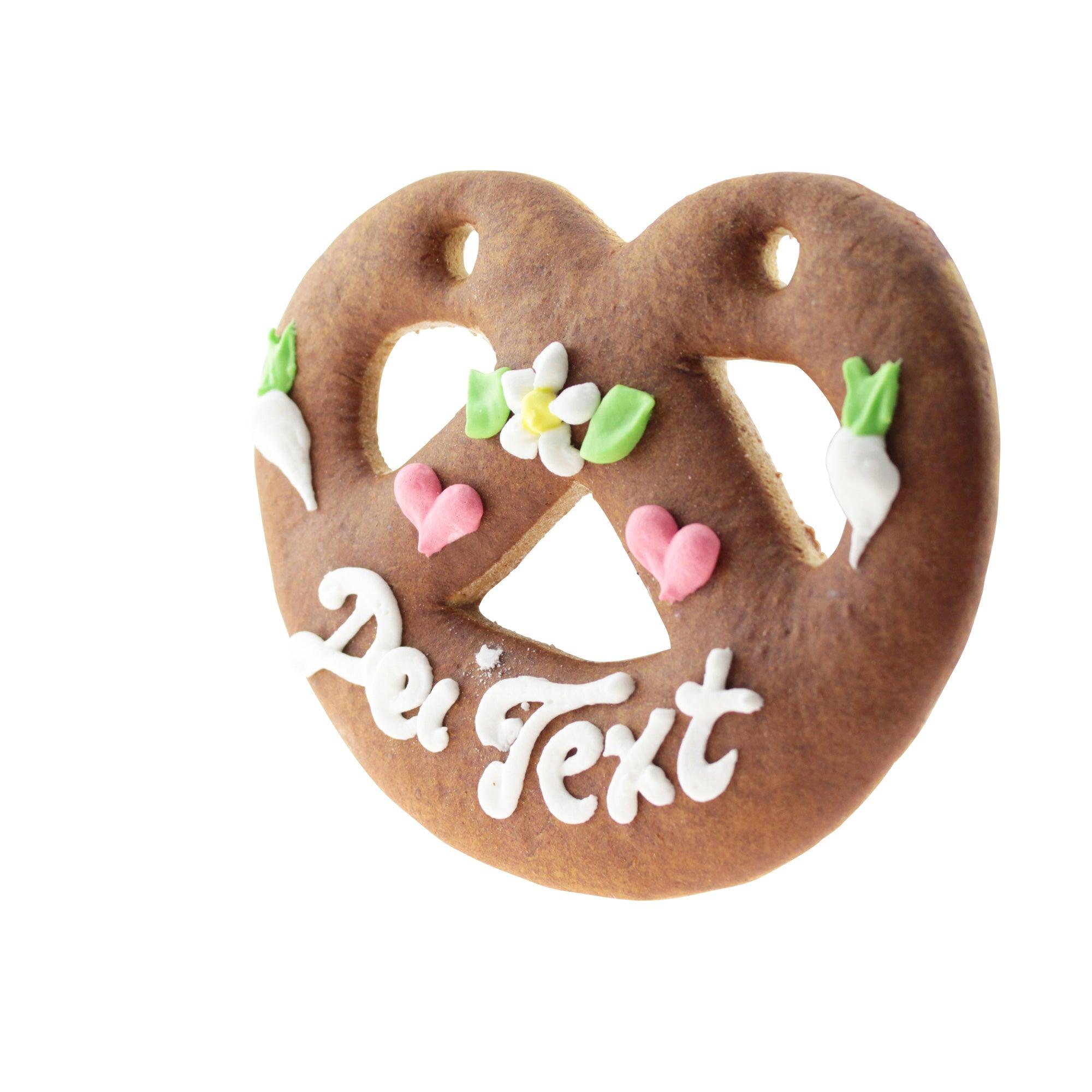 Herzförmiger Lebkuchen in Brezenform mit weiß-blauem Zuckerrand und Aufschrift, aus Braunem Teig, ca. 12 x 15 cm.