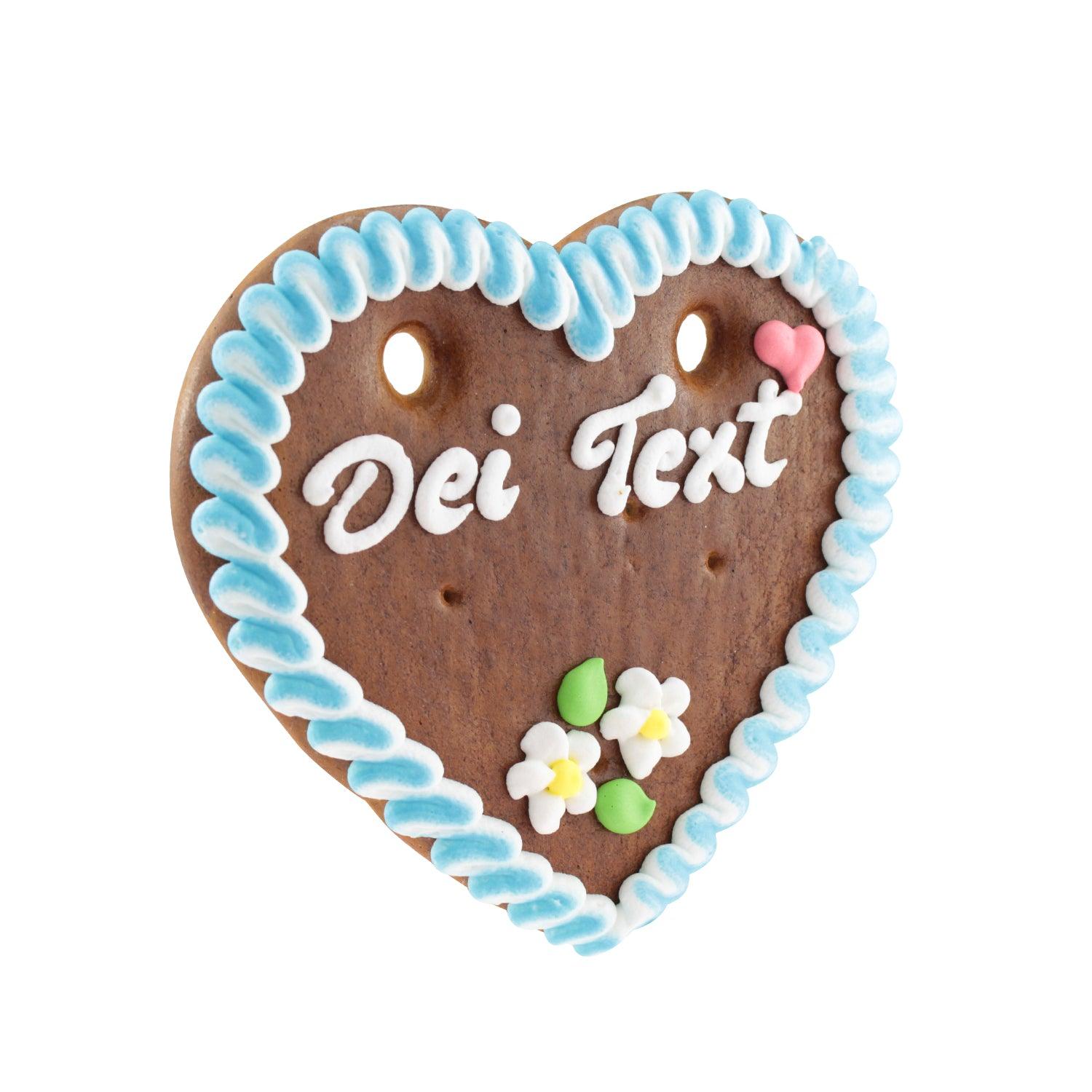 Herzförmiges Lebkuchenherz mit weißem Zuckerrand, rosa Zuckerschrift und Blümchen-Dekor, braun, ca. 14 × 17 cm.