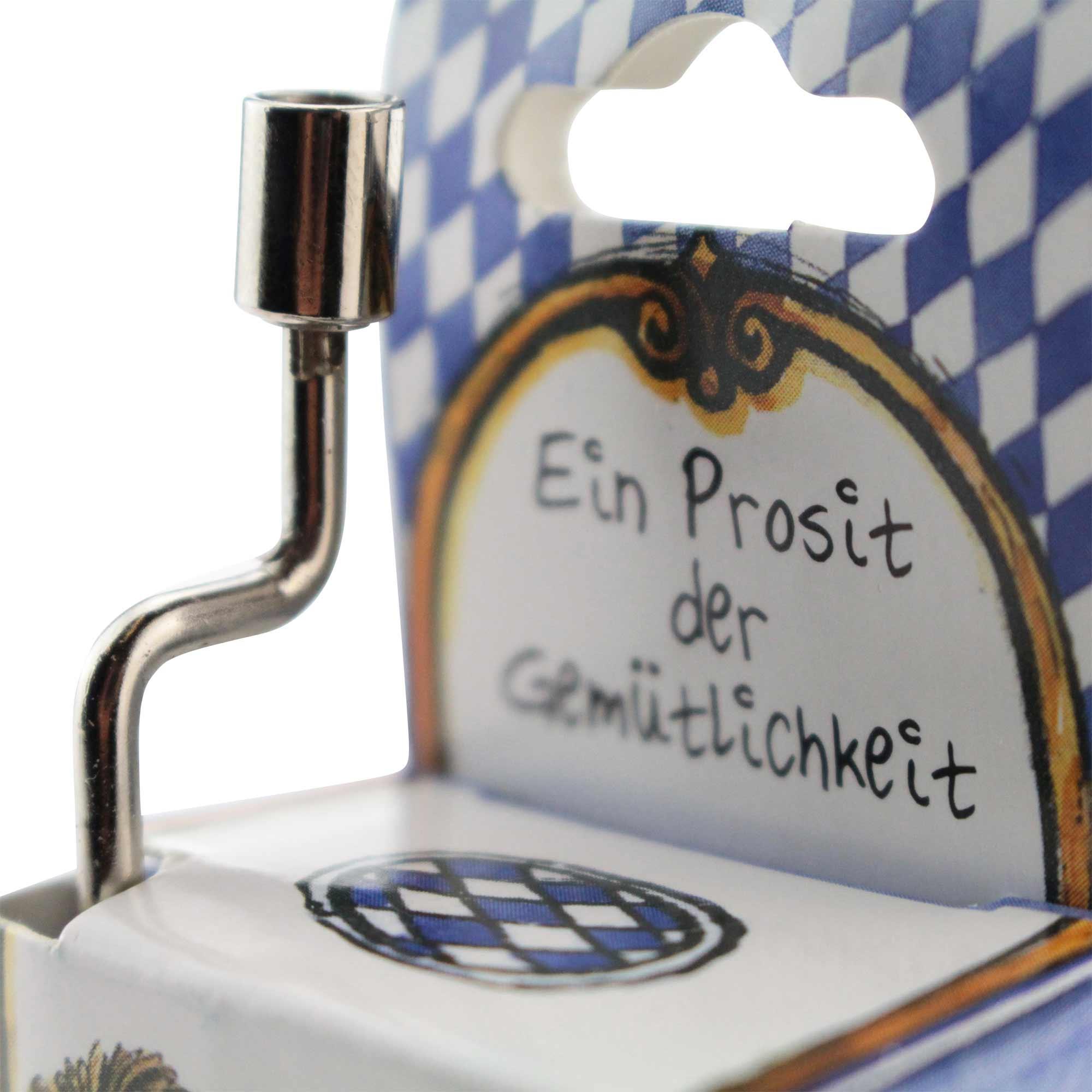 Mini-Drehorgel mit Handkurbel, rechteckig, Holzoptik, blaues Etikett, Schriftzug „Ein Prosit der Gemütlichkeit“, 8×4×2 cm.