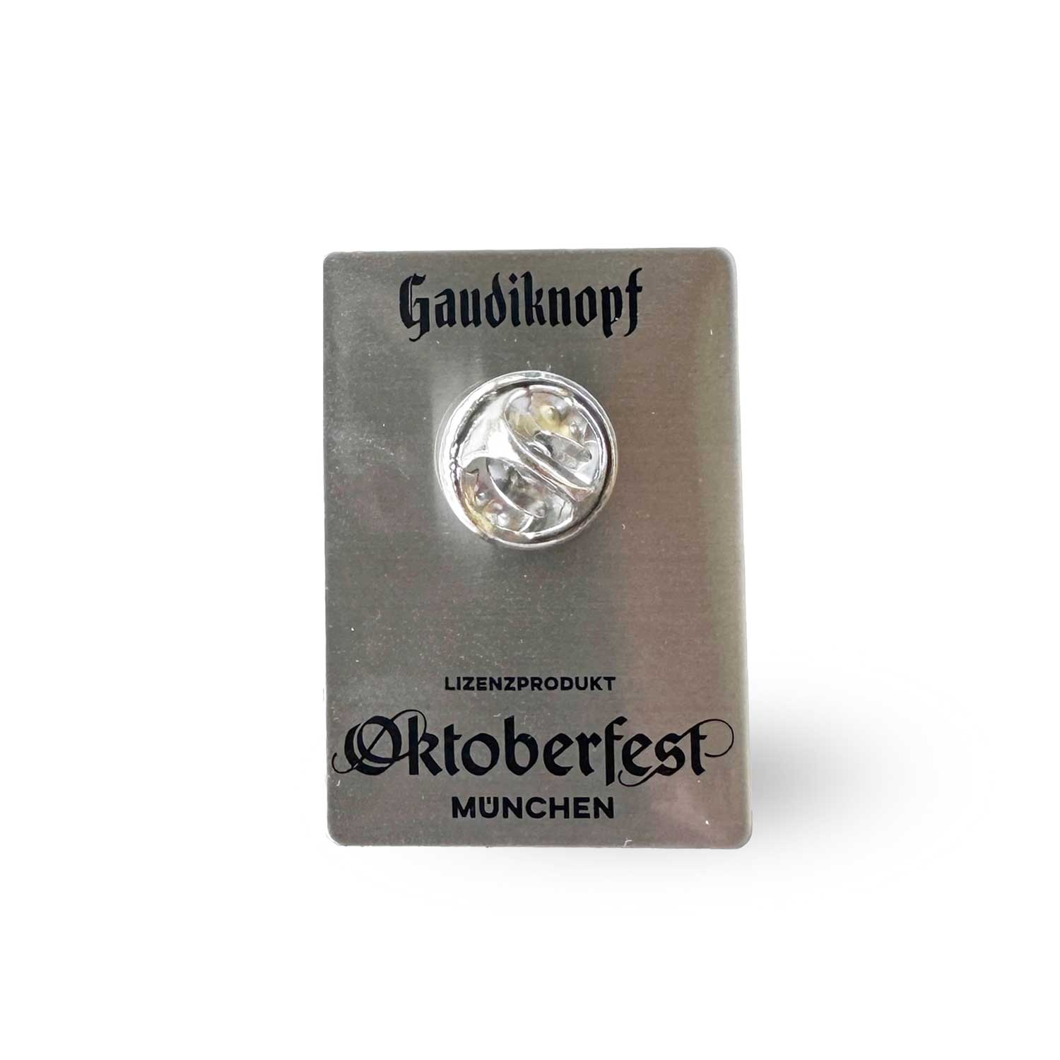 Rückseite des offiziellen Pin Oktoberfest 2025 mit "Gaudiknopf" und "München" Schriftzug.