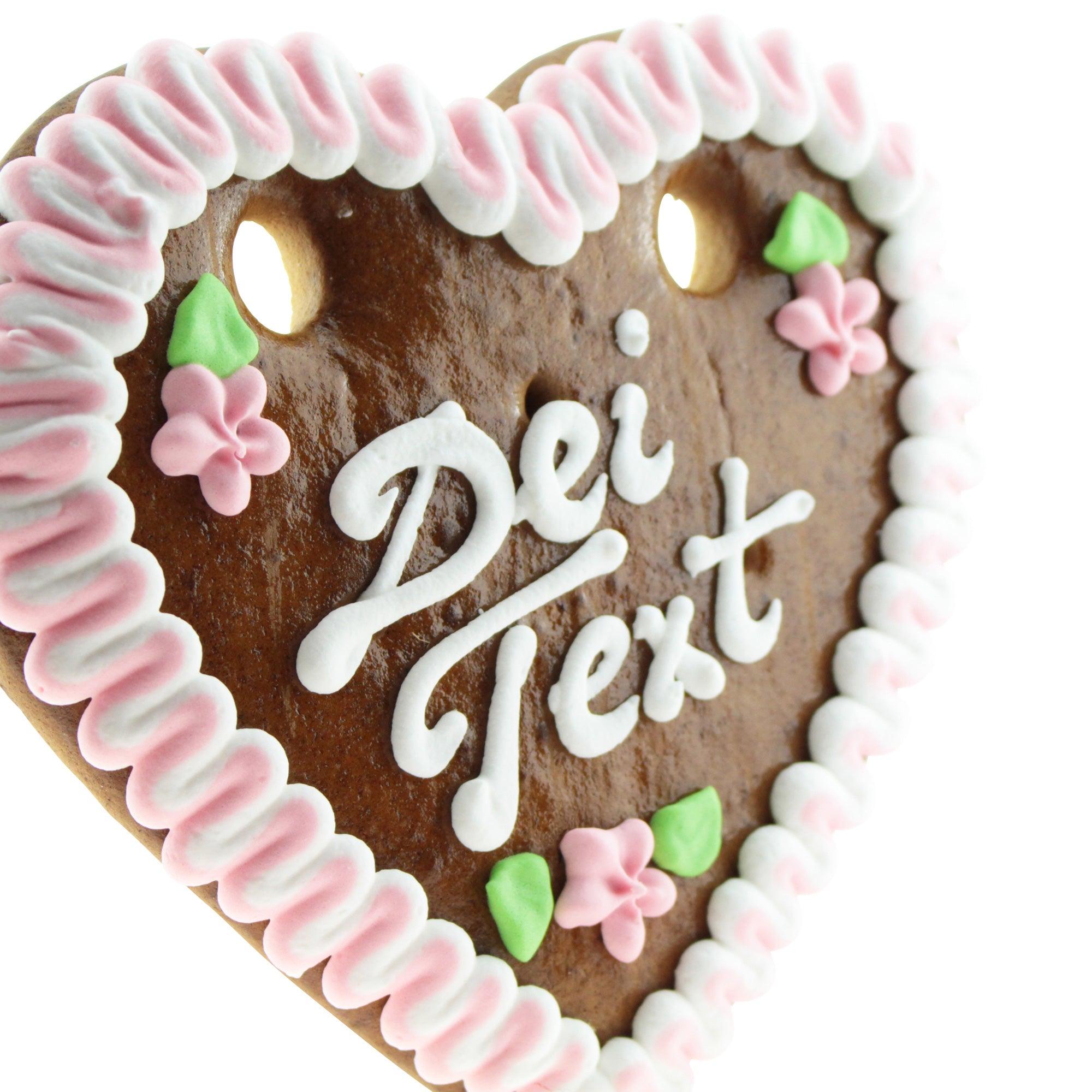 Herzförmiges Lebkuchenherz mit weißer und rosa Zuckerverzierung, Aufschrift und individueller Namenszeile.