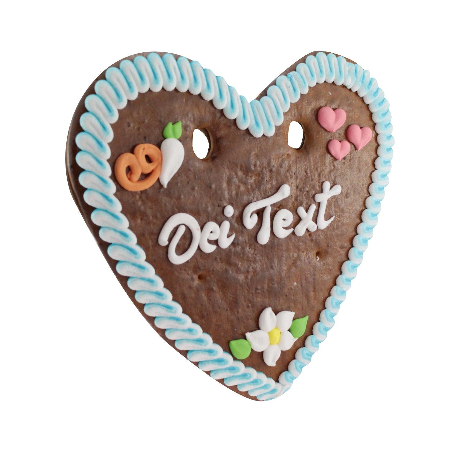 Herzförmiges Lebkuchenherz aus braunem Teig mit rosa Rand, weißer Zuckerschrift und Blütenmotiv, 32 × 28 cm, 180 g.