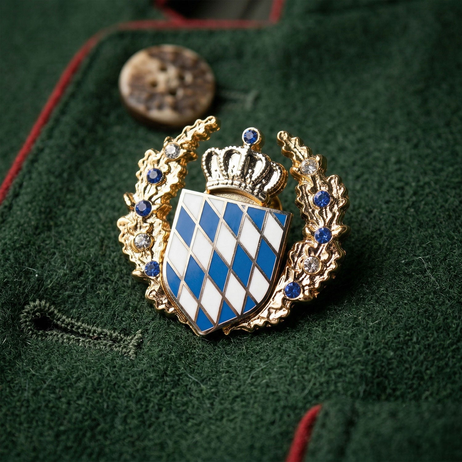 Bayerischer Wappen-Pin goldfarben mit blauen und weißen Rauten. Umrahmt von Kranz mit blauen und klaren Steinen.