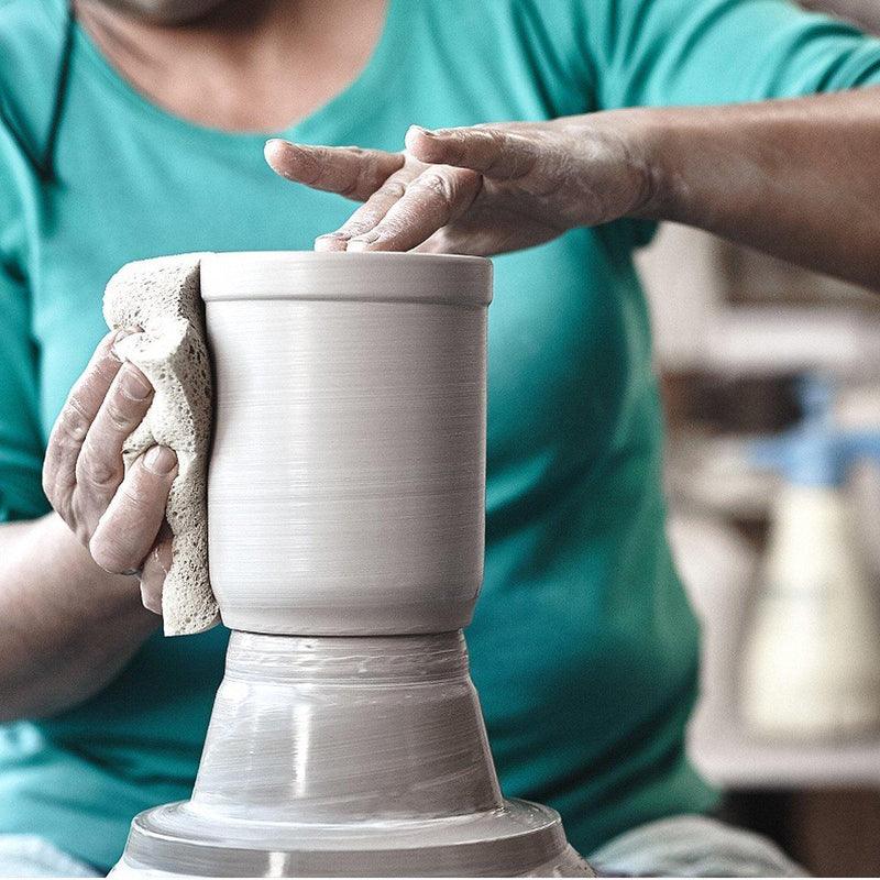 Handwerker formt mit Schwamm feinen PREMIUM Bierkrug Freistaat Bayern auf Töpferscheibe.
