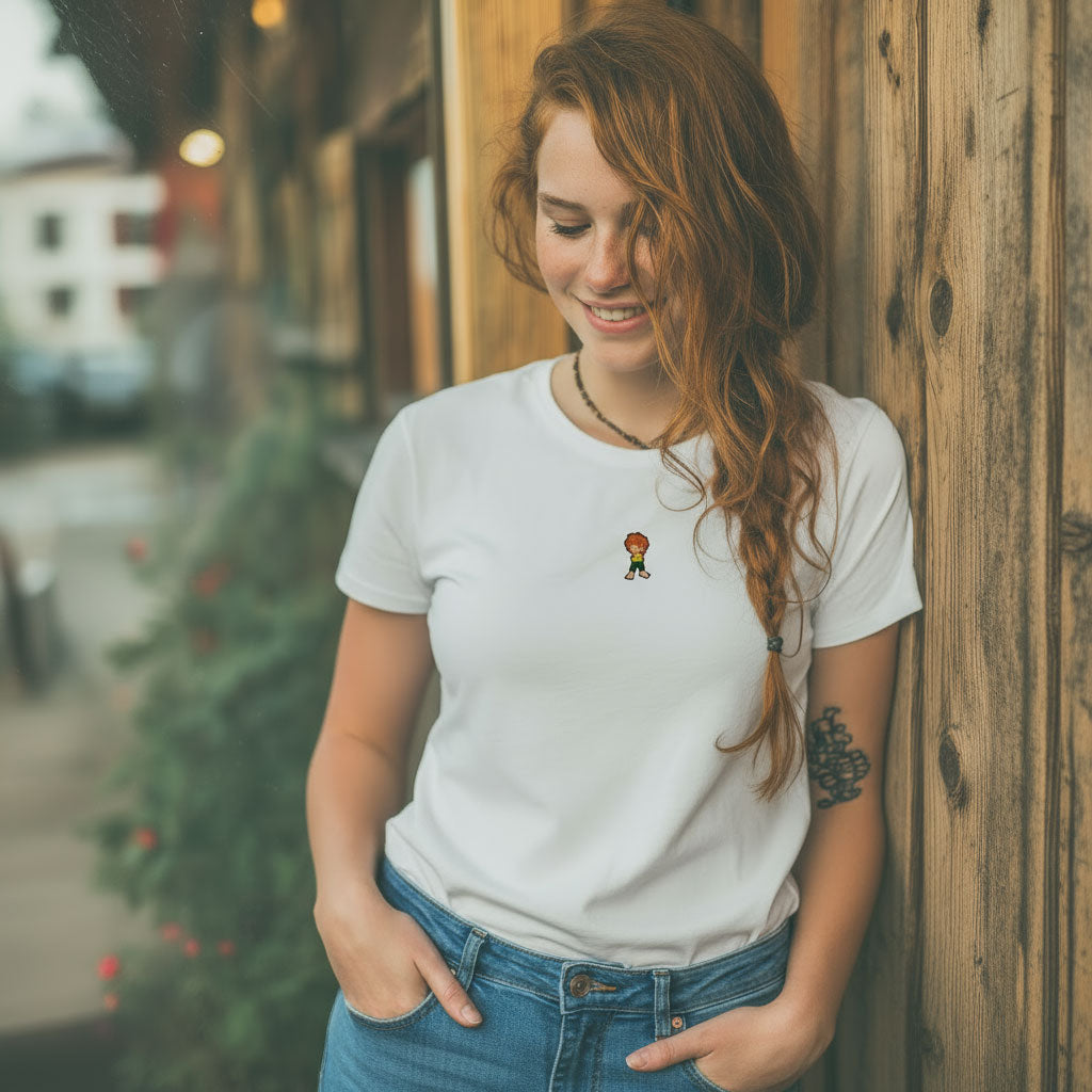 Glückliche junge Frau mit geflochtenen roten Haaren trägt weißes Pumuckl Damen T-Shirt "Grantla" mit kleinem Kobold-Motiv.