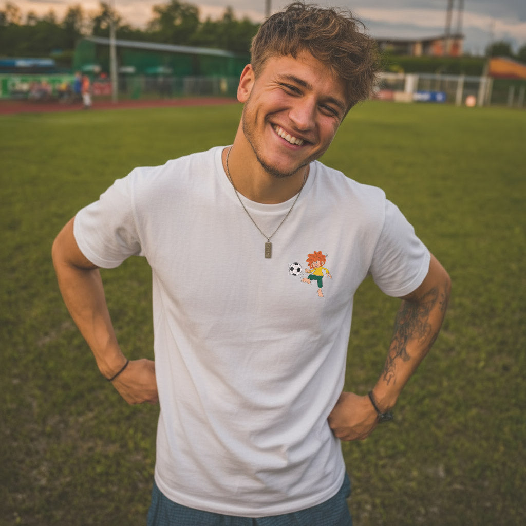 Lachender Mann trägt weißes ®Pumuckl Herren T-Shirt "Fußball Kobold" auf grünem Fußballfeld.