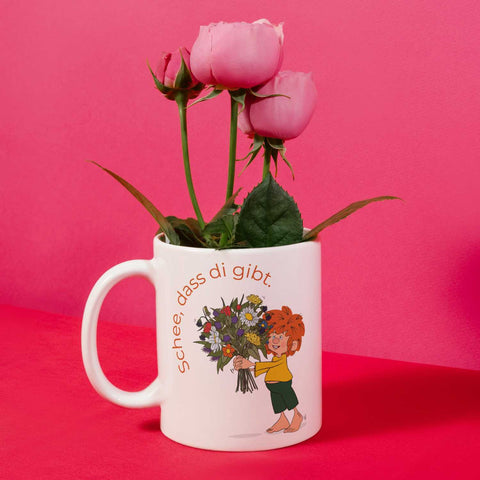 Pumuckl Tasse „Schee, dass di gibt.“ mit rosa Rosen vor pinkem Hintergrund
