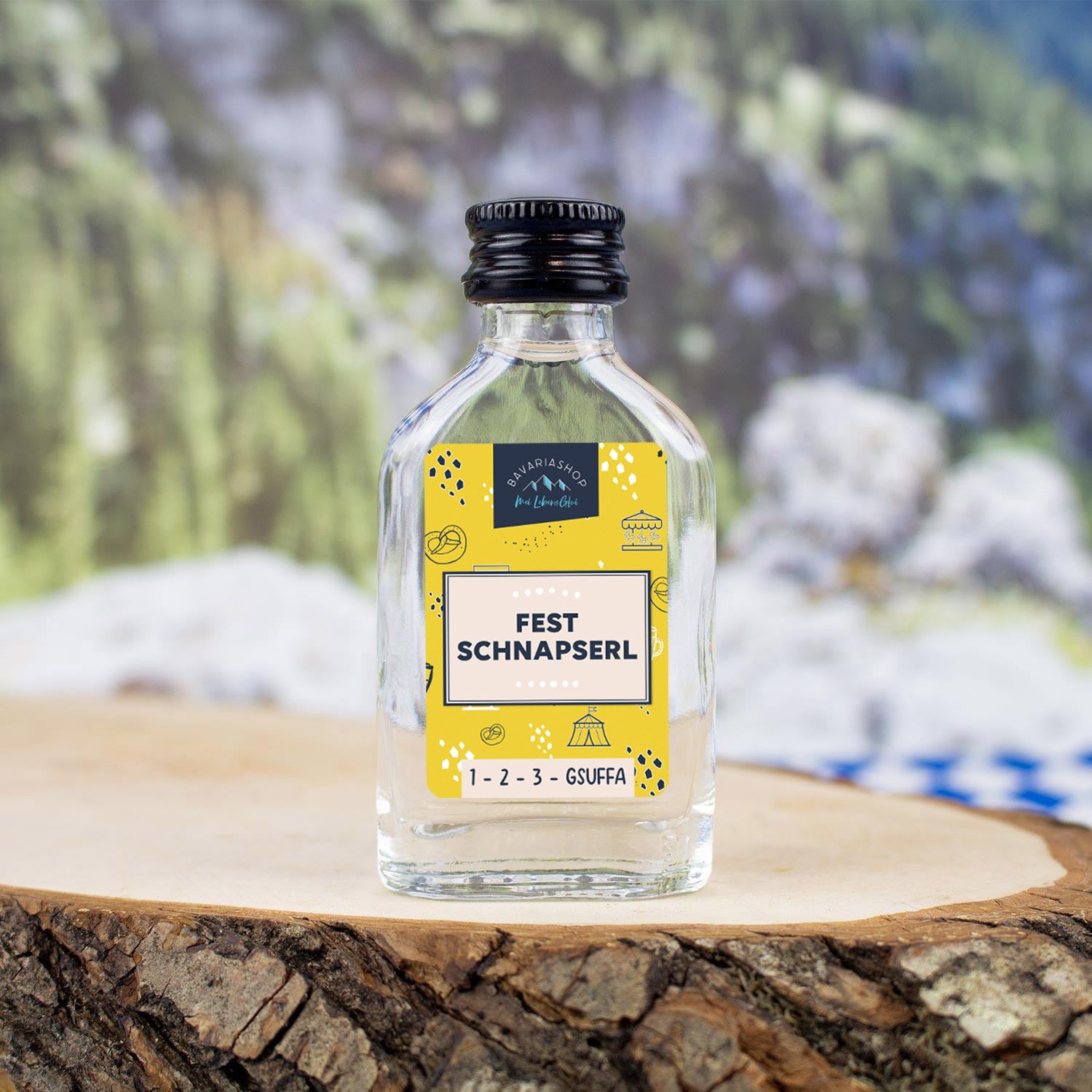 Klare Mini-Glasflasche mit 20 ml Obstler, 38 % vol., rund, mit weiß-blauem Etikett und bunter Aufschrift „Fest Schnapserl“.