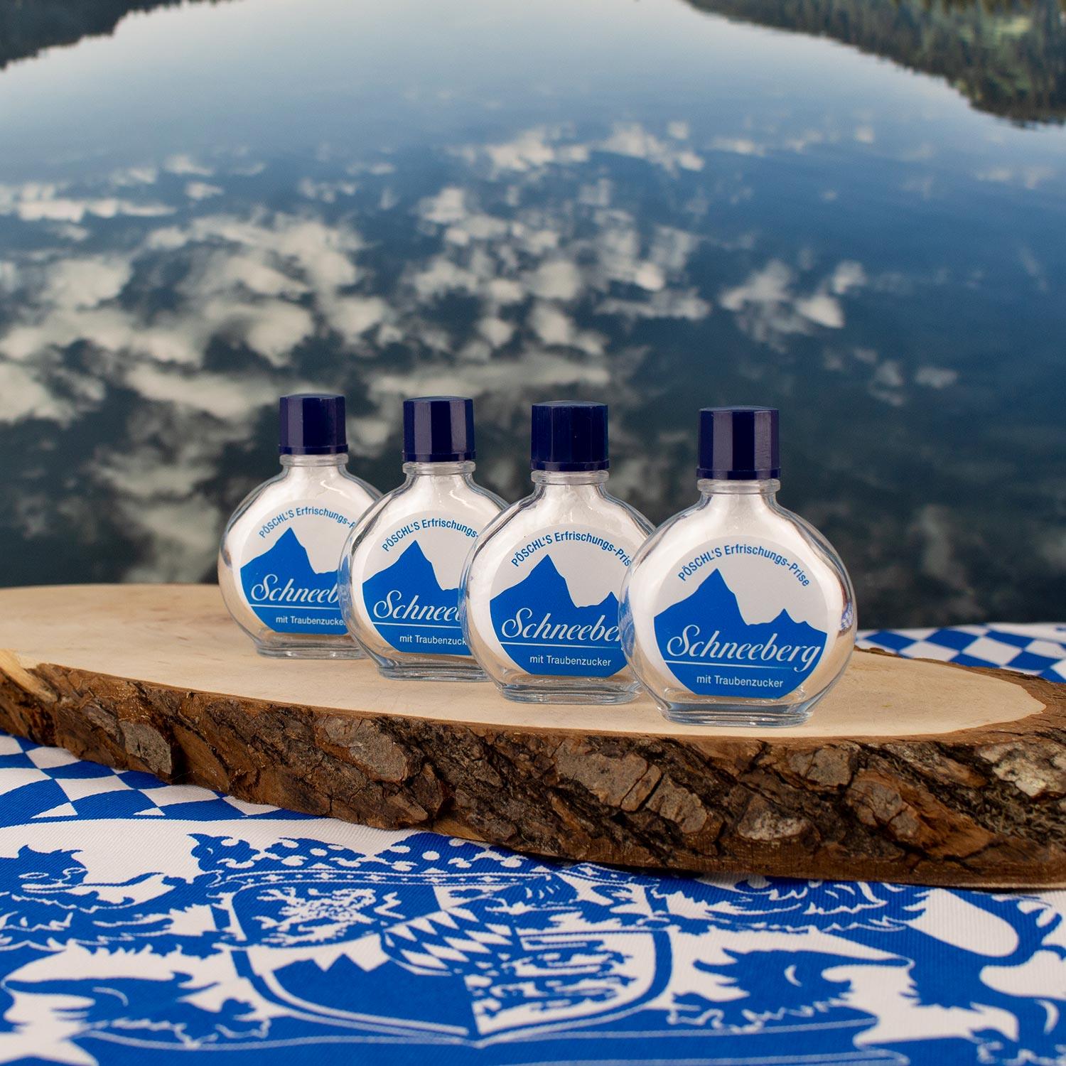Vier Pöschl's Schneebär Erfrischungs-Prise mit Traubenzucker auf Holzscheibe vor See-Panorama