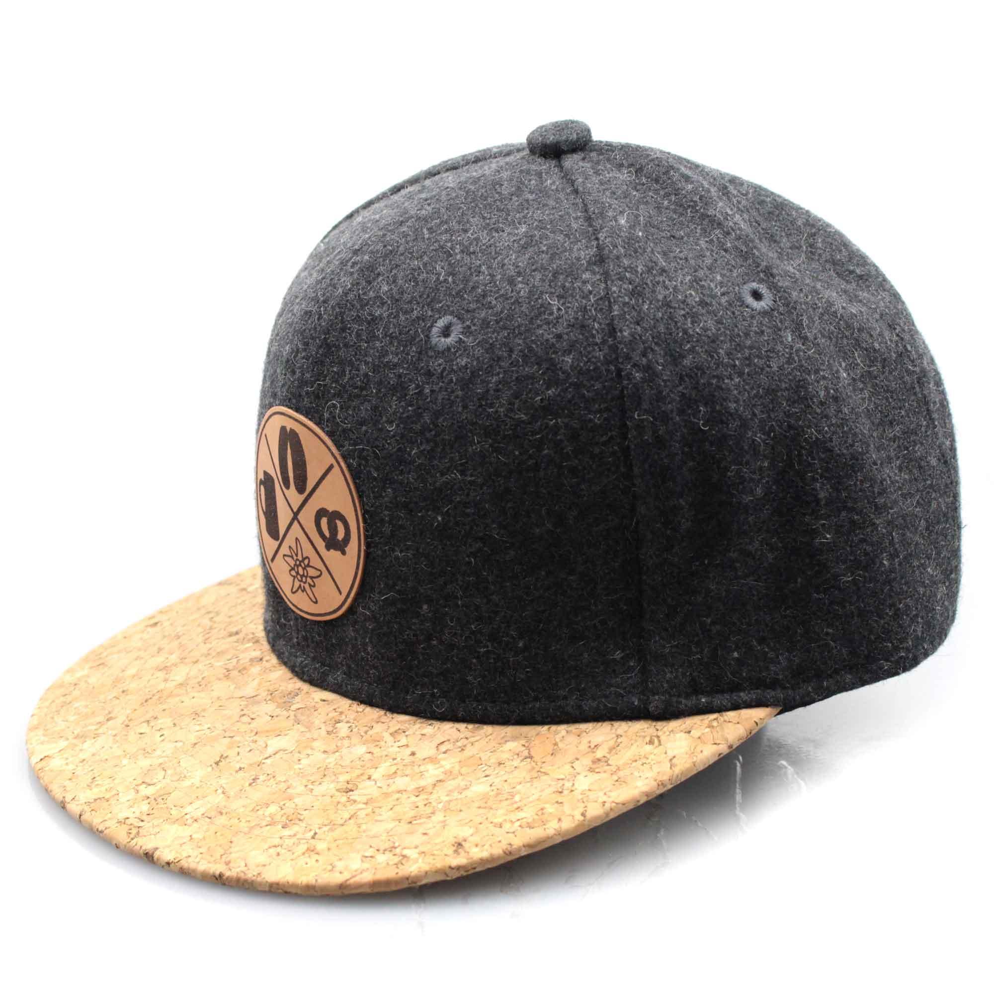 Graue Snapback-Cap in Filzoptik mit braunem Korkschild und rechteckigem Patch mit Aufschrift „Boarisch“.
