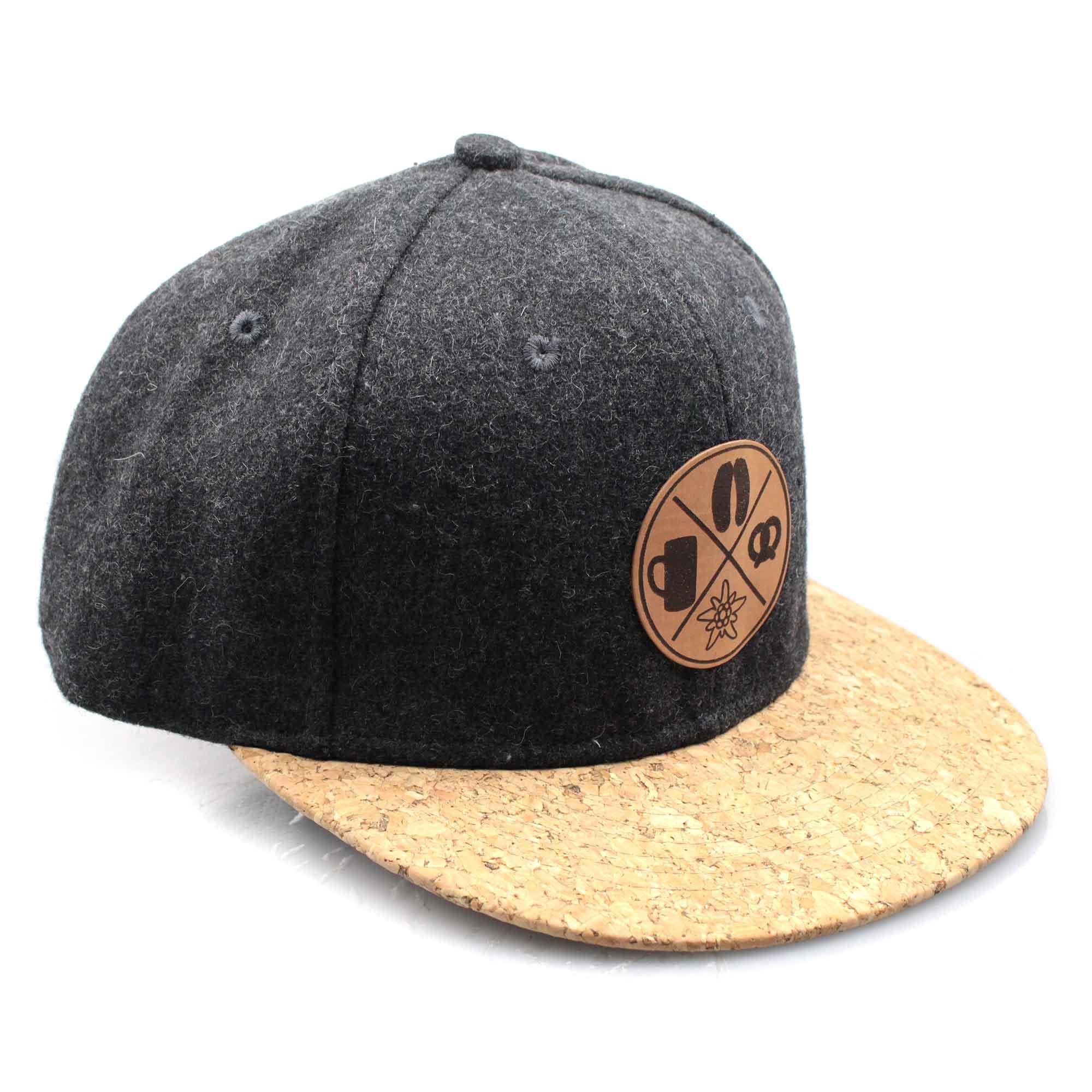 Graue Snapback-Cap in Filzoptik mit braunem Korkschild und rechteckigem Patch mit Boarisch-Schriftzug.