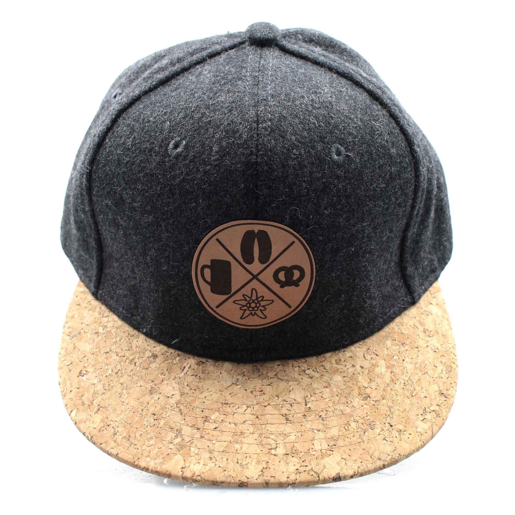 Snapback-Cap in grauer Filzoptik mit braunem Korkschild und gesticktem Patch mit „Boarisch“-Schriftzug.