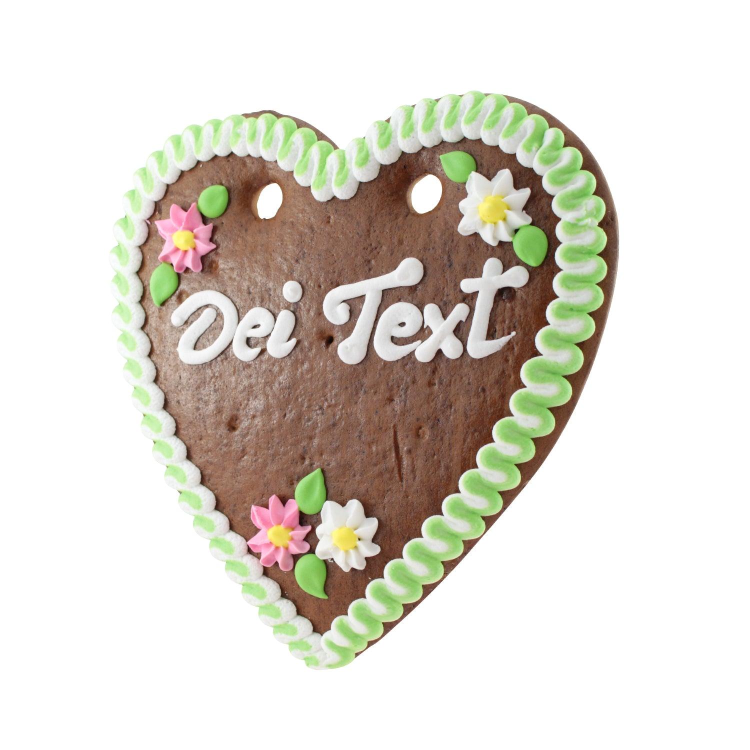 Herzförmiges Lebkuchenherz mit weißer Zuckerschrift, rosa Rand und Blumenverzierung, handgefertigt in Bayern, ca. 22 x 23 cm.